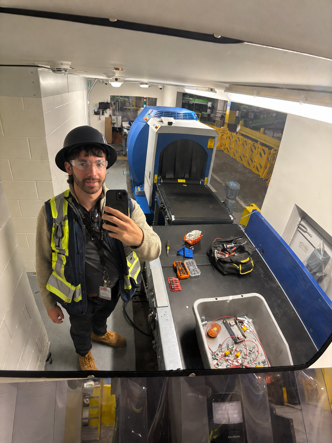 Joshua, Buildomize founder, in hard hat and hi-vis vest working on conveyor equipment on site