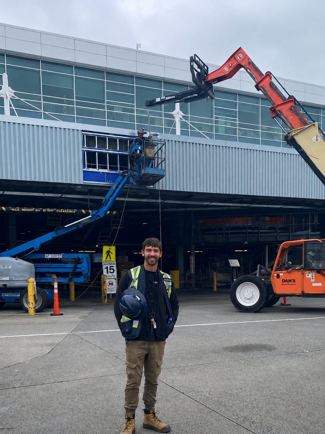 Joshua, founder of Buildomize, on a commercial job site in a hi-vis vest holding a hard hat